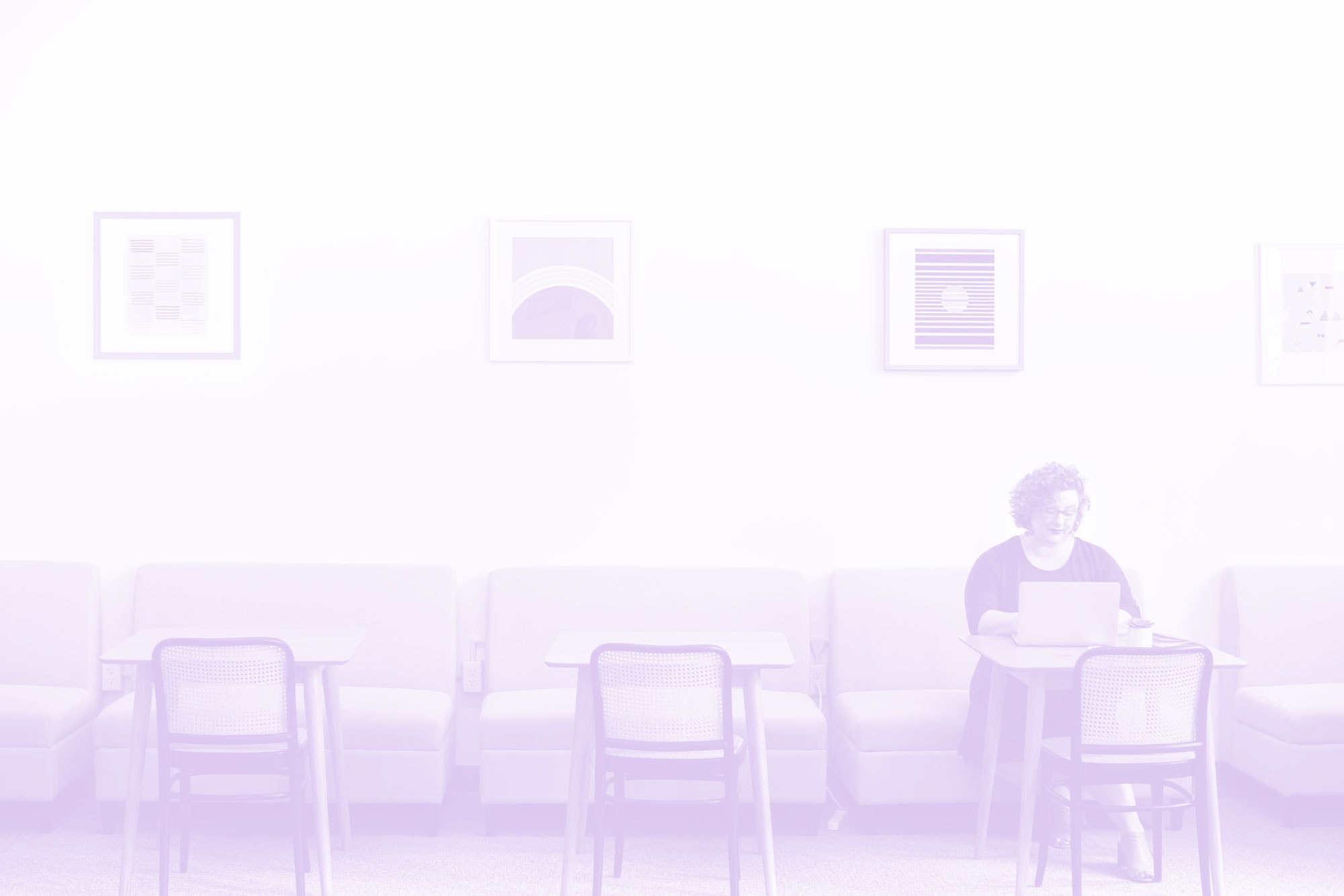 purple tinted image of woman working in cafe