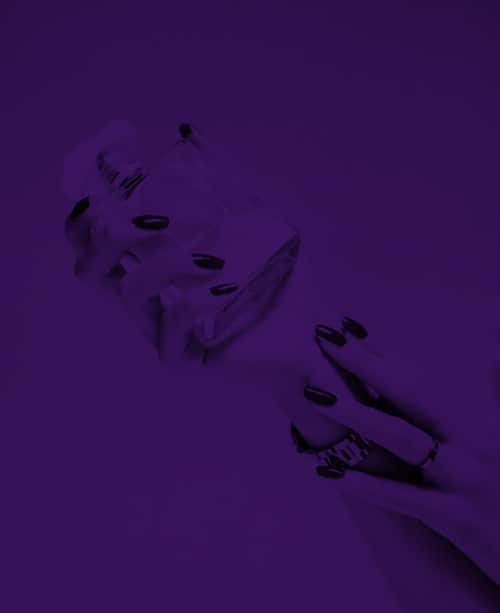 purple tinted image of hands holding a perfume bottle