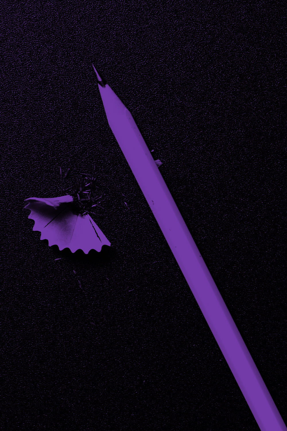 black background with a purple pencil and pencil shaving